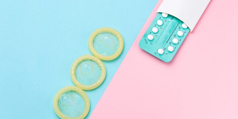 Contraceptive pills and condoms on colored background. View from above. Concept of birth control Contraceptive pills and condoms on colored background. View from above. Concept of birth control